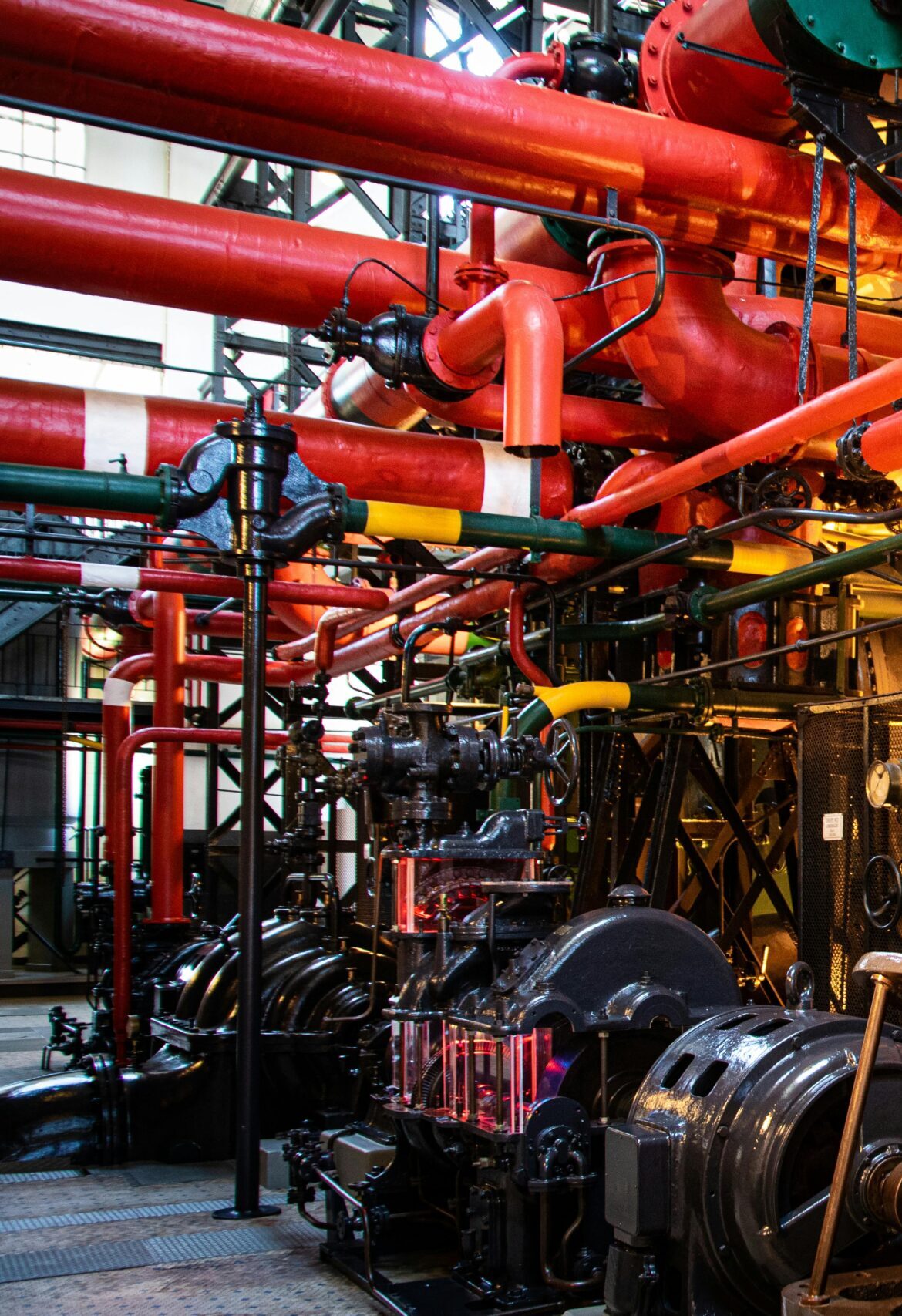 Vibrant industrial machinery with red pipes and complex equipment in a factory.
